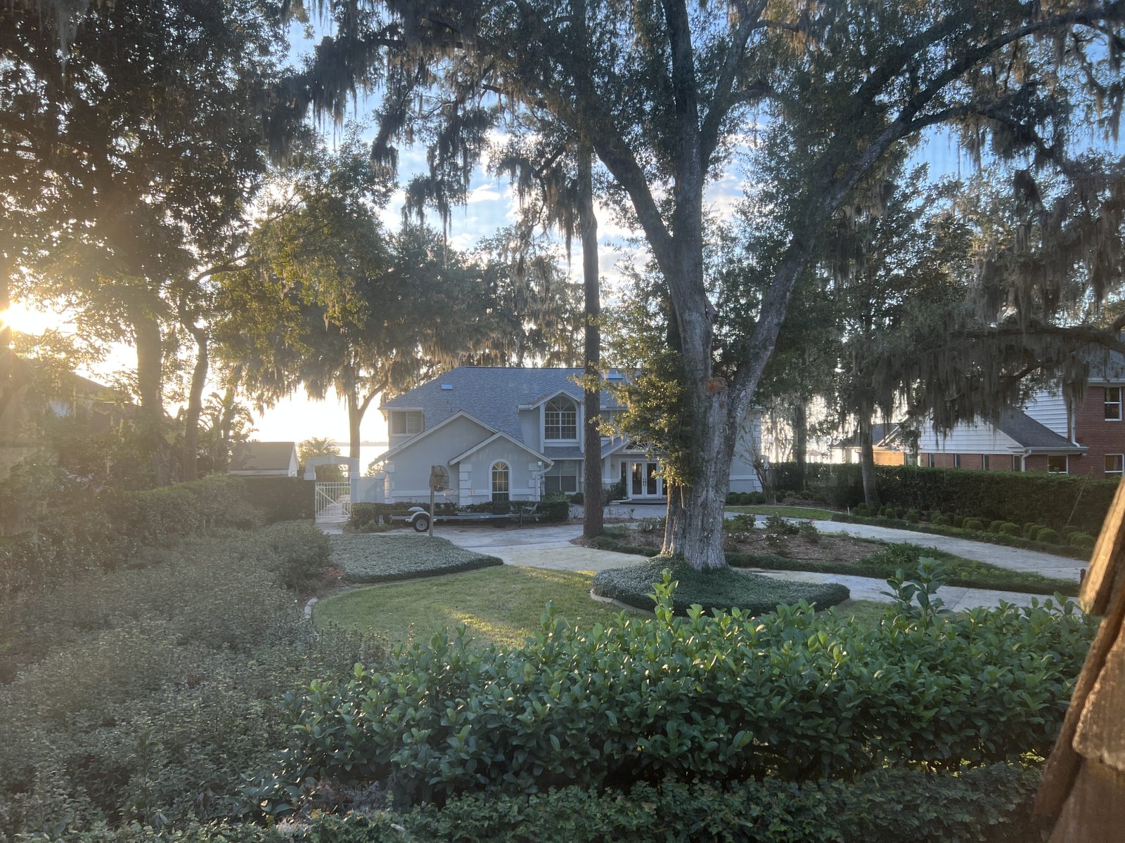 Live oaks draped with Spanish moss in front of a two story home near the river in Jacksonville, Duval County, Florida